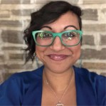 a photo of a women in a blue shirt with green glasses 