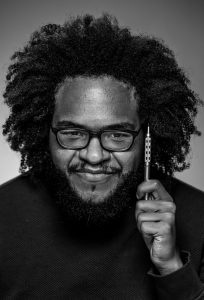 A black and White photo of a man with glasses holding a pen 