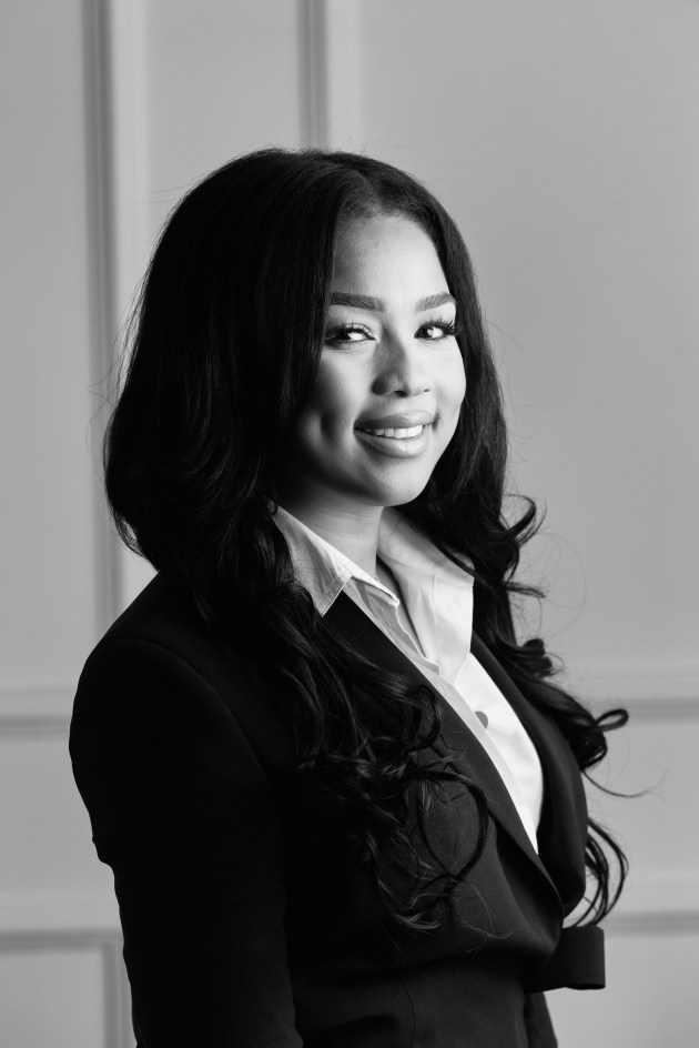 a black-and-white photo of a smiling woman wearing a white shirt and black blazer.
